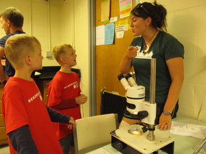 Teacher talking with students by microscope
