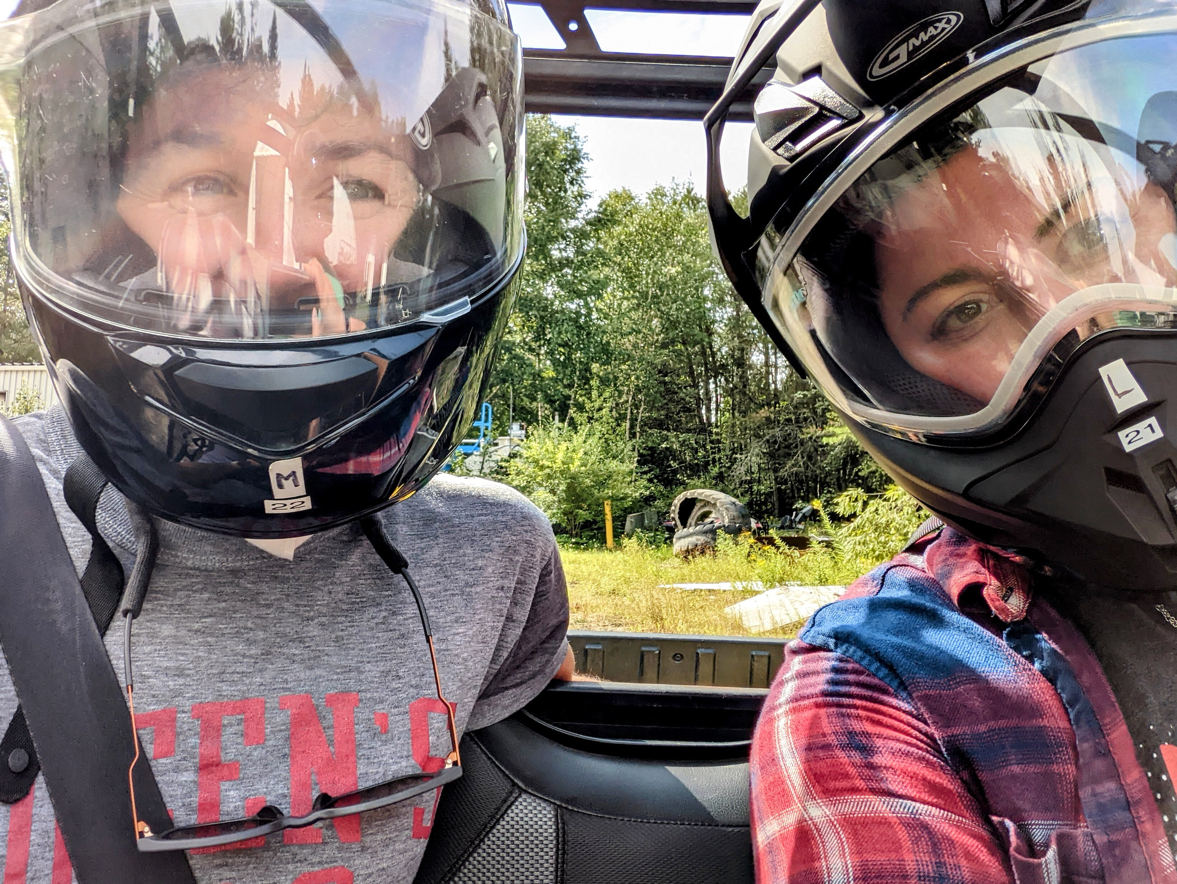Hilary Dugan and Grace Wilkinson wearing helmets in the back of a UTV.