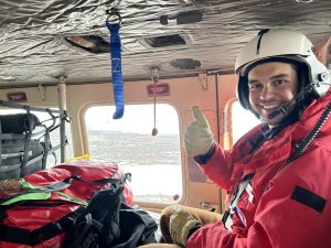 Charlie wearing winter gear and helmet while sitting inside airplane