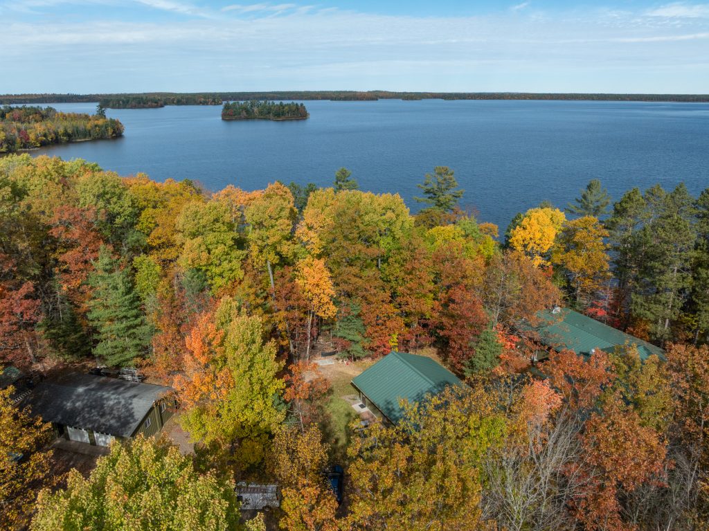 Drone view of Trout Lake Station and Trout Lake far distance in the fall. Tops of station buildings can be seen in foreground.